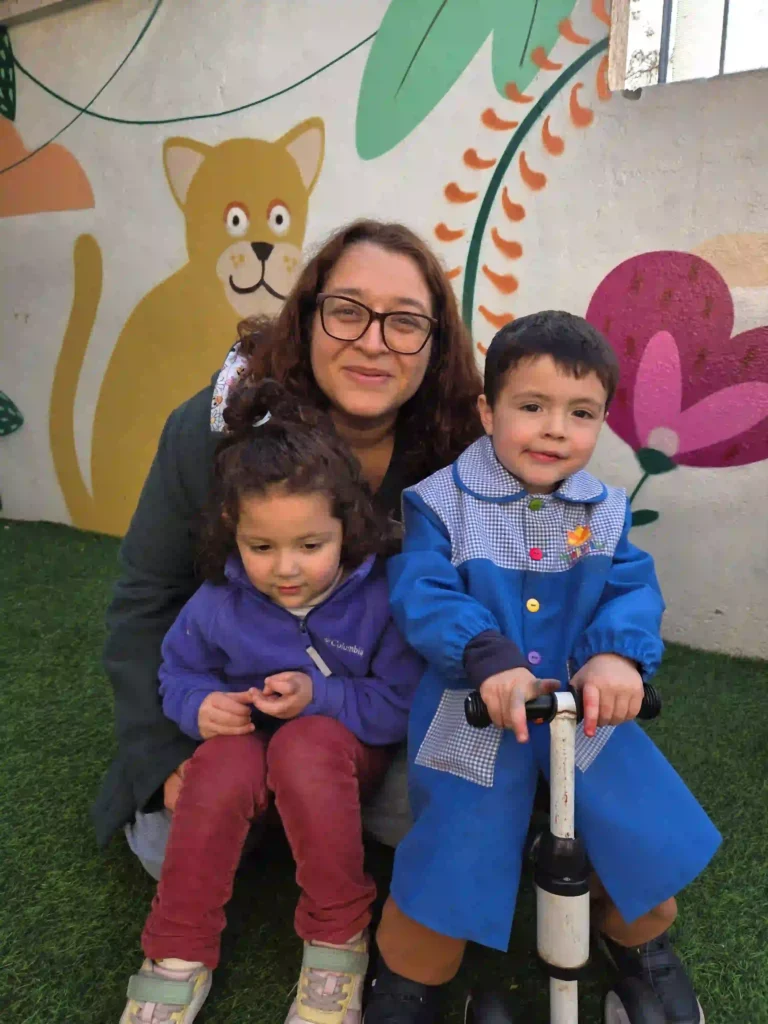 Educadora acompañando a niños en espacio de juego al aire libre del jardín infantil