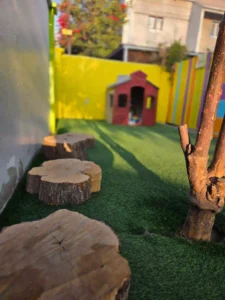 Sendero sensorial con troncos de madera en patio educativo infantil